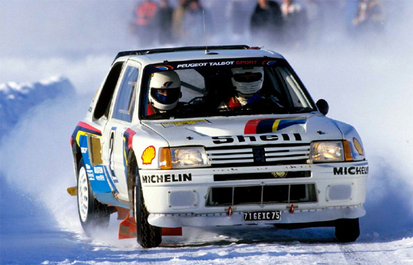 Vintage photo of a Peugeot 205 T16 rally car drifting in the snow during the